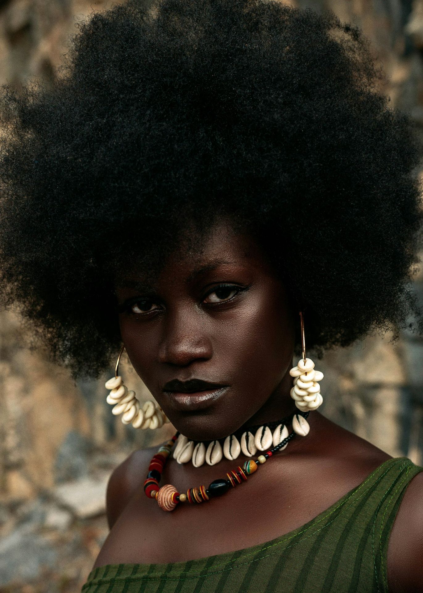 a woman with an afro wearing a necklace and earrings